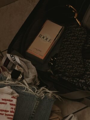 A Lancome perfume box packed with fashion items in a suitcase.