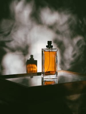A stylish perfume bottle casting shadows on a reflective surface, creating a moody ambiance.