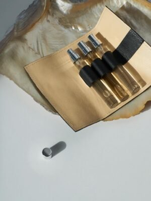 Stylish perfume sample bottles in a leather case on a seashell, showcasing elegance on a white surface.