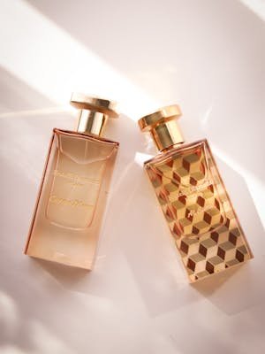 Two elegant perfume bottles with geometric designs in a bright setting.